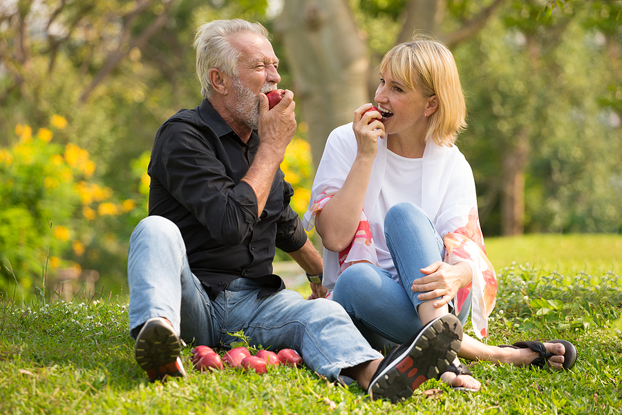 Happy Senior Couple Relaxing In Park Eating Apple Together Morni